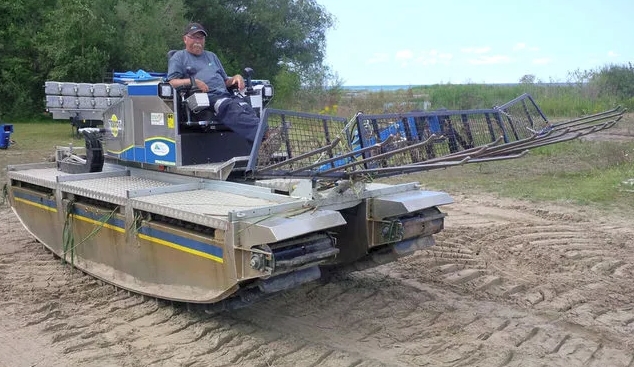 Amphibious vehicle cutting Phragmites below the waterline in Ontario